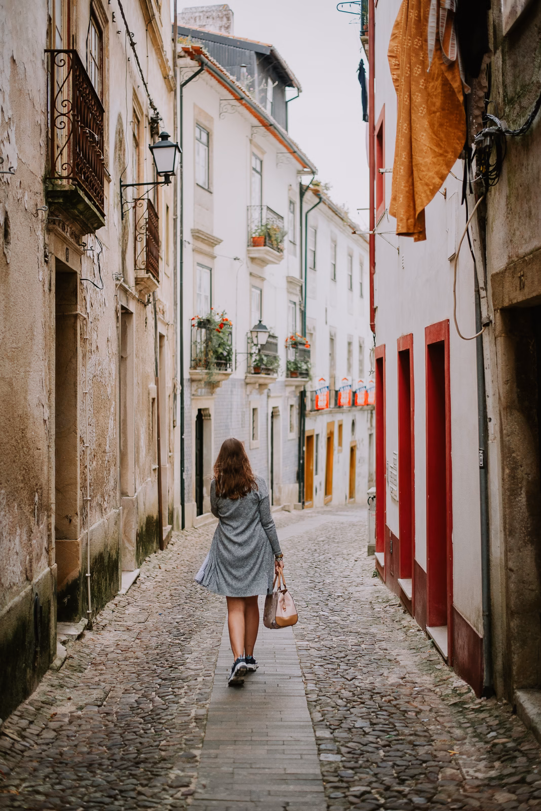 A cobbled alley in the Alta quarter of Coimbra with laundry hanging between buildings