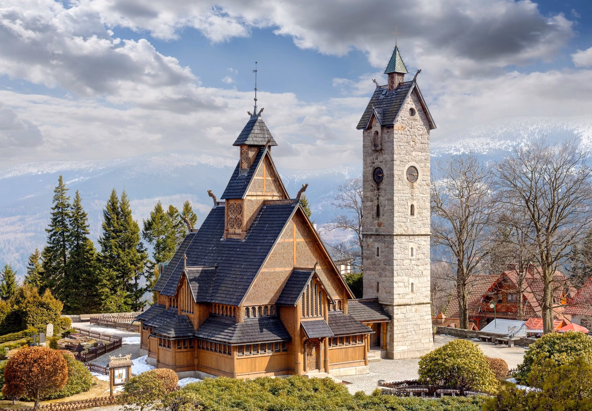 Wooden Wang Chapel in Karpacz with a stone tower and Giant Mountains forest in the background