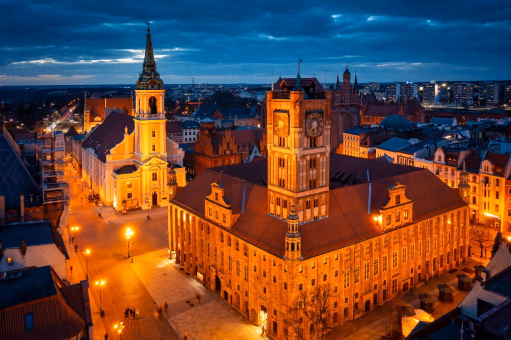 Aerial night view of the illuminated Torun Town Hall tower with clock on the Old Market Square