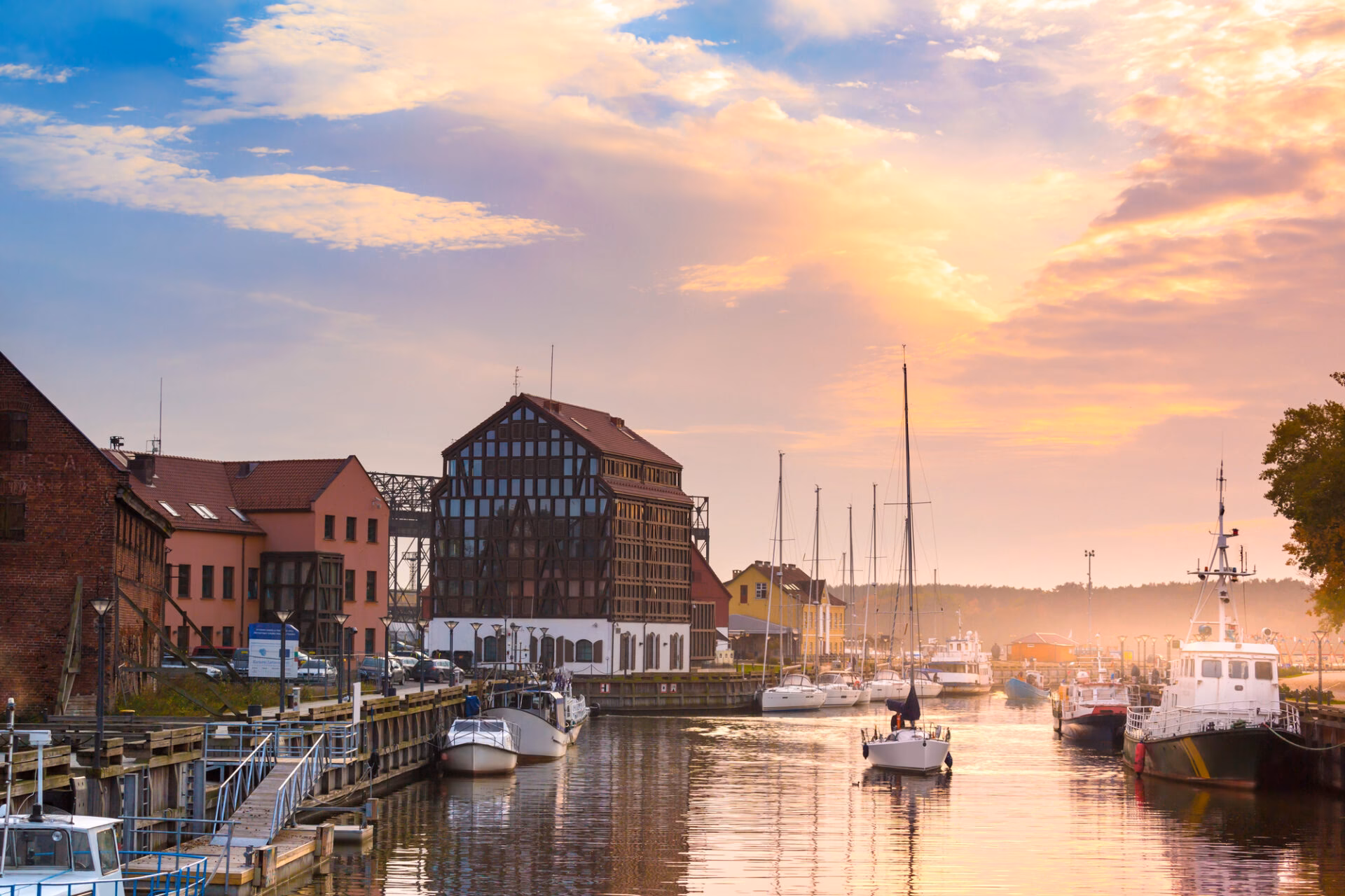 Klaipėda harbour with a half-timbered building and sailboats at sunset