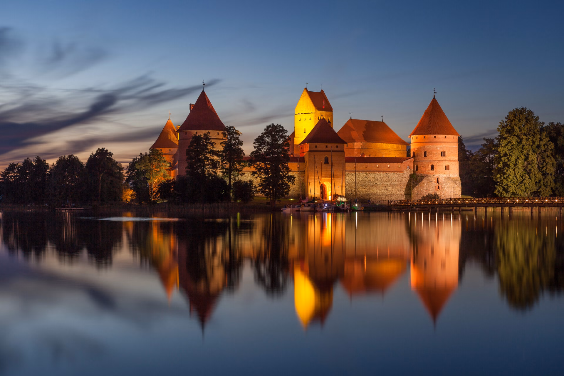 Trakai Castle lit up after dark, reflected in Lake Galvė