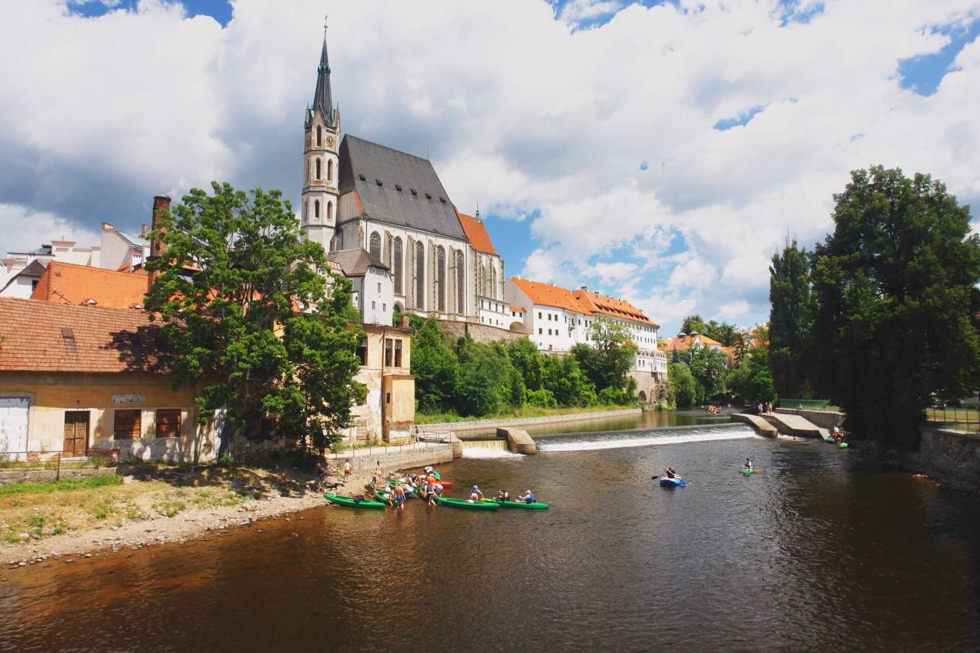 Rafting through the centre on the Vltava Paddlers on a weir below St Vitus's Church in Cesky Krumlov