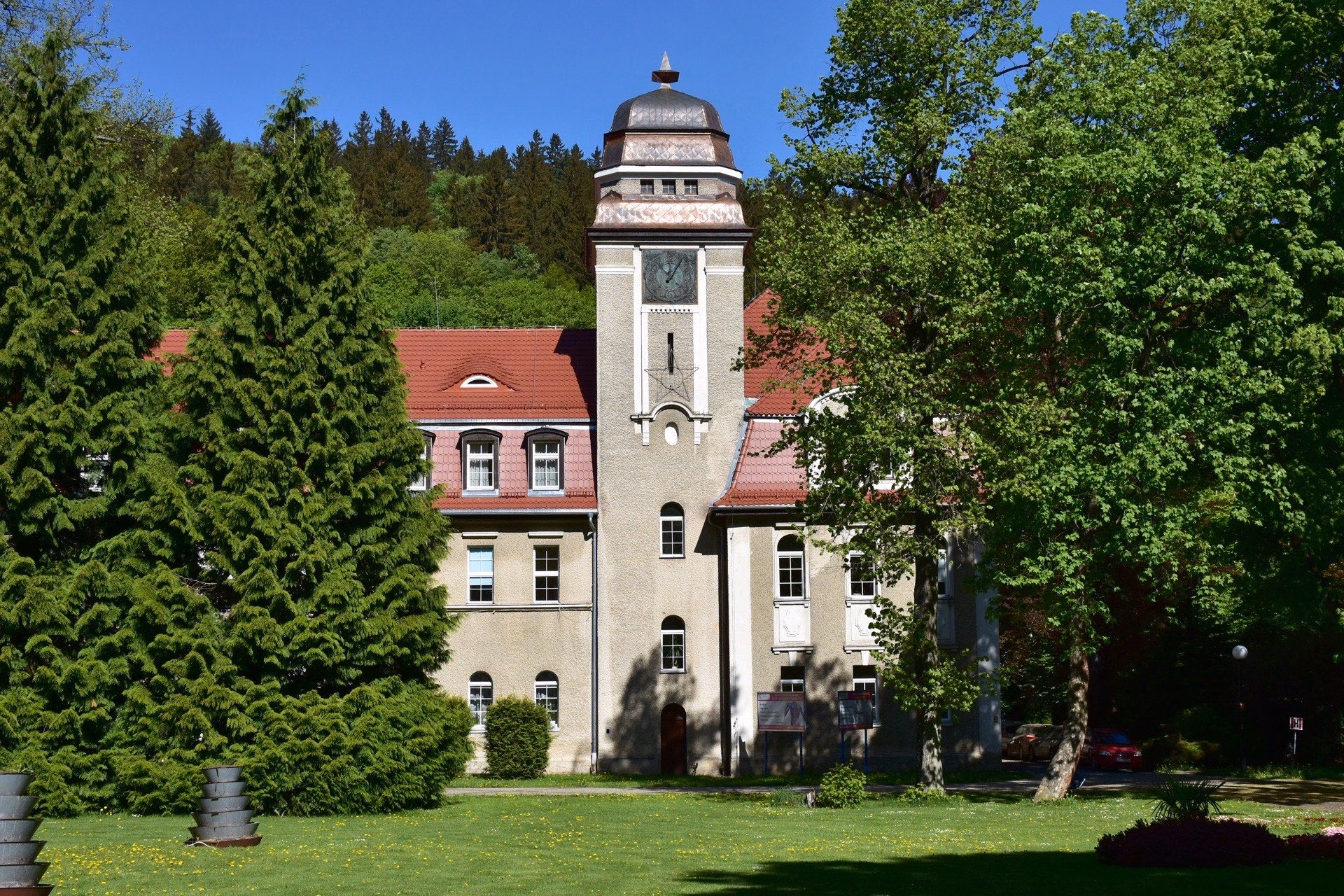 Historic spa building with a clock tower in a park in Duszniki-Zdrój