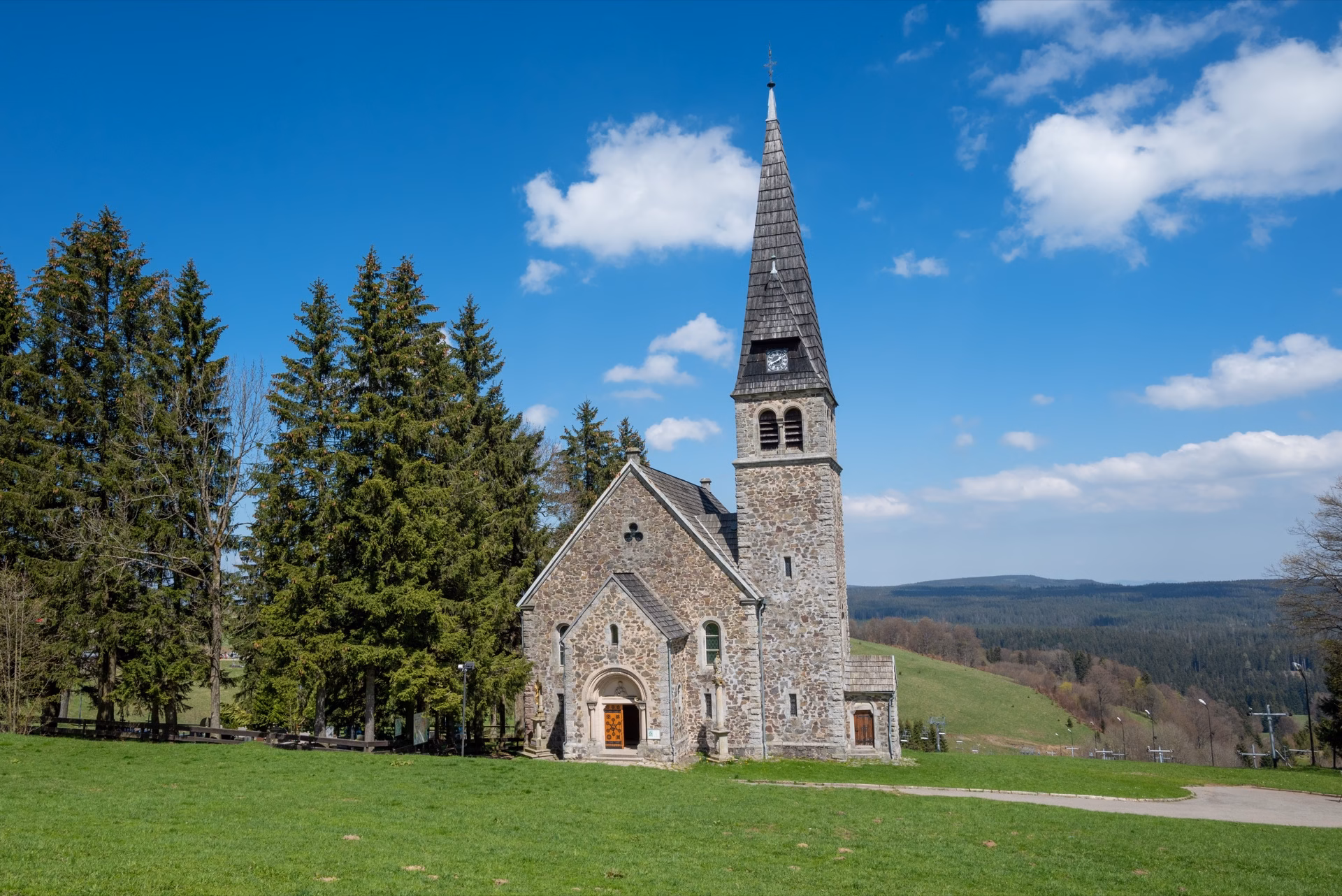 Stone church in Zieleniec with a mountain meadow and ski slope in the background