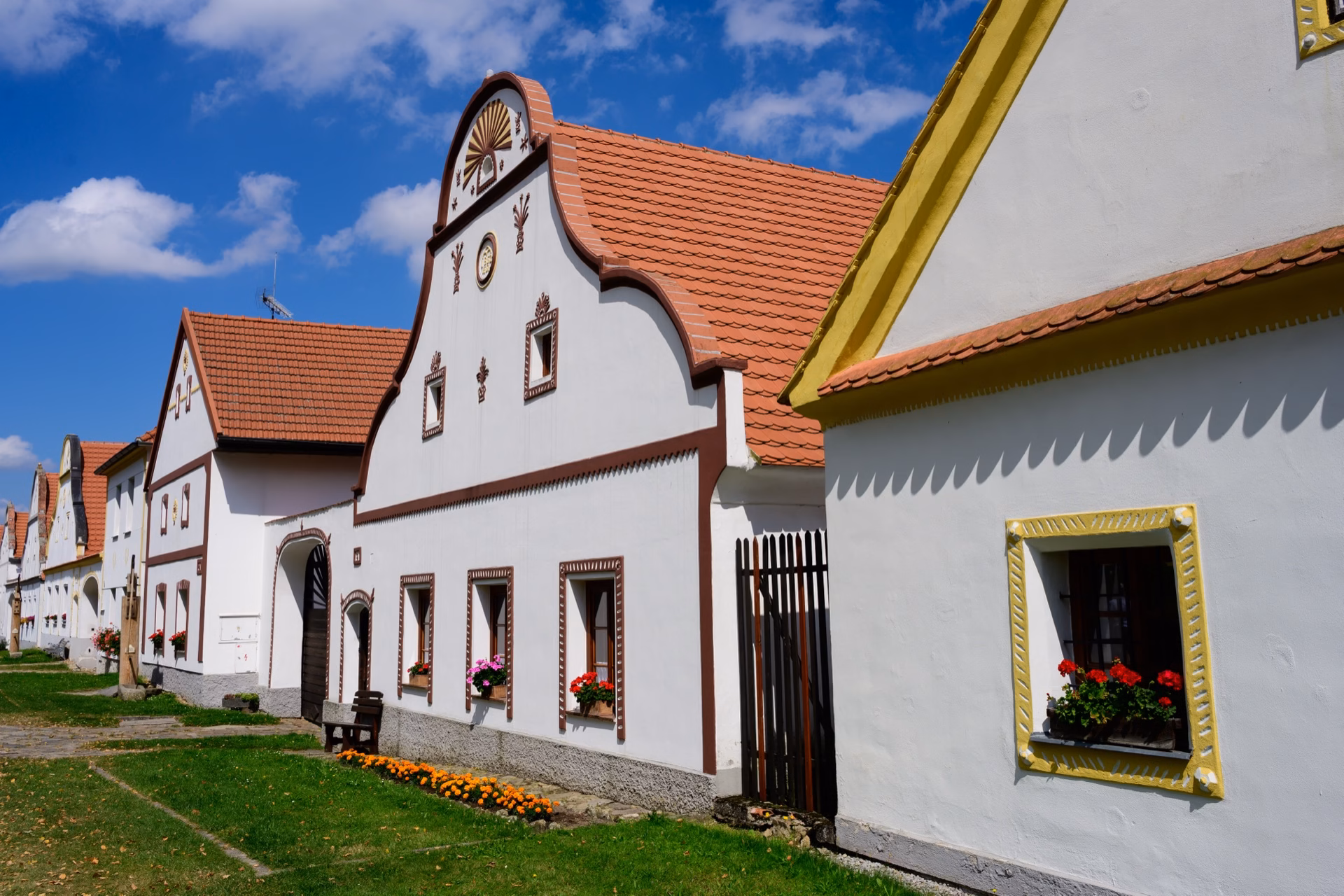 Decorated gables and a brick entrance gate to a farmstead in the UNESCO village of Holašovice