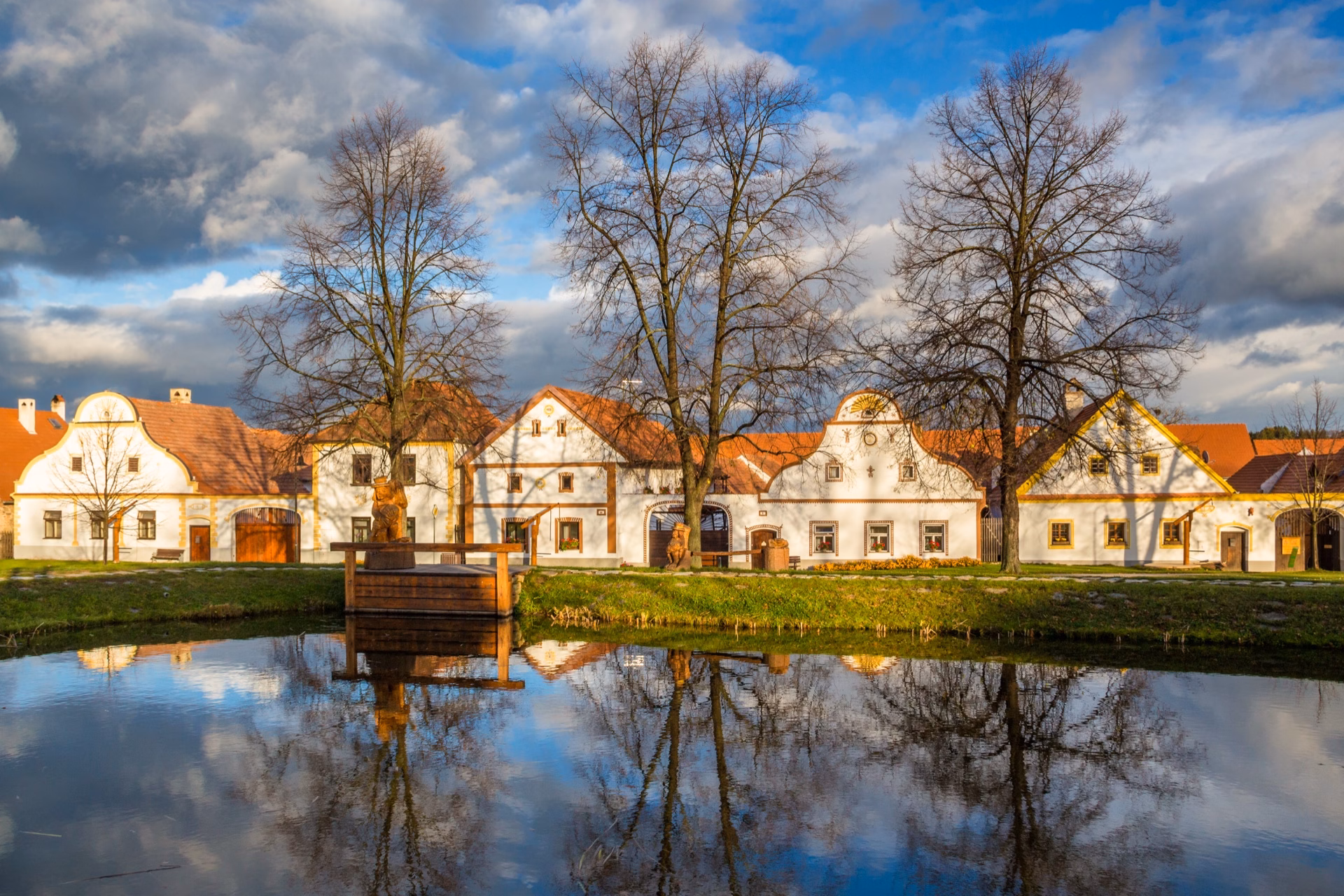 The village pond in Holašovice out of season, with folk baroque farmsteads behind bare trees