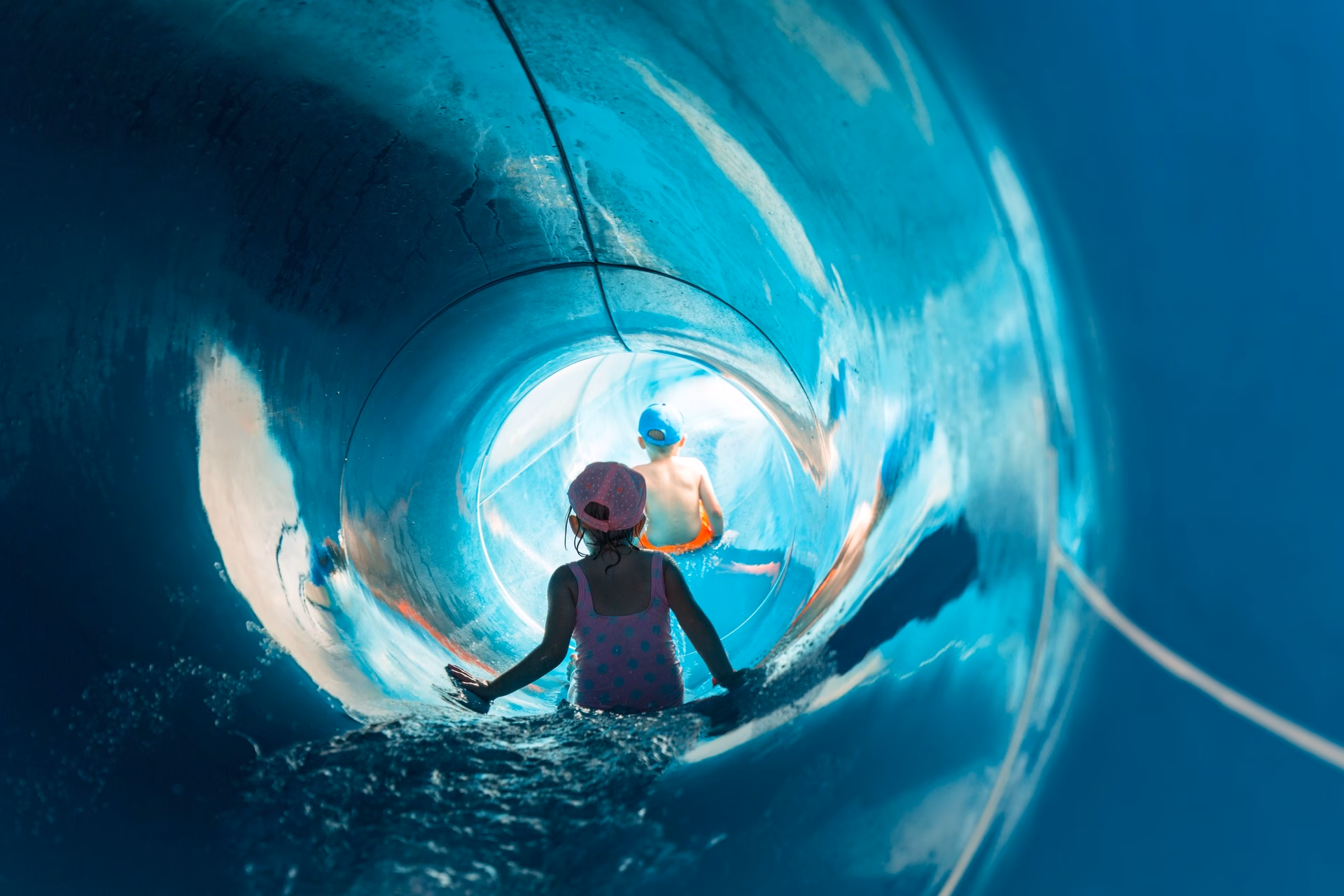 Kinderen glijden van een waterglijbaan in een overdekt zwembad – illustratieve foto