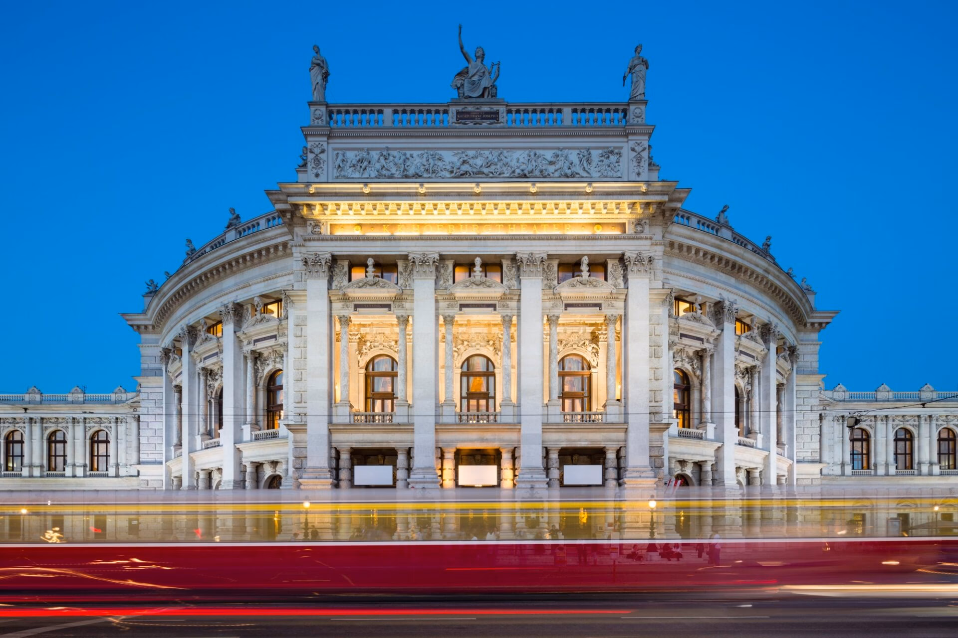 Burgtheater in Wenen 's avonds verlicht met een passerende tram