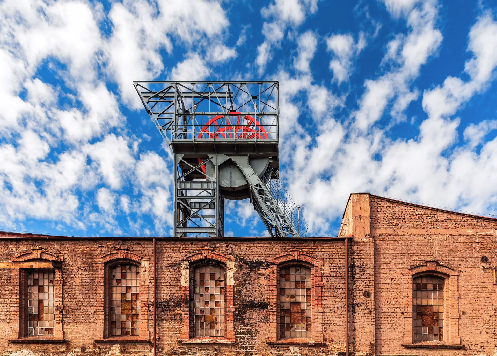 Winding tower of a former coal mine above a brick building, a reminder of Katowice's industrial past